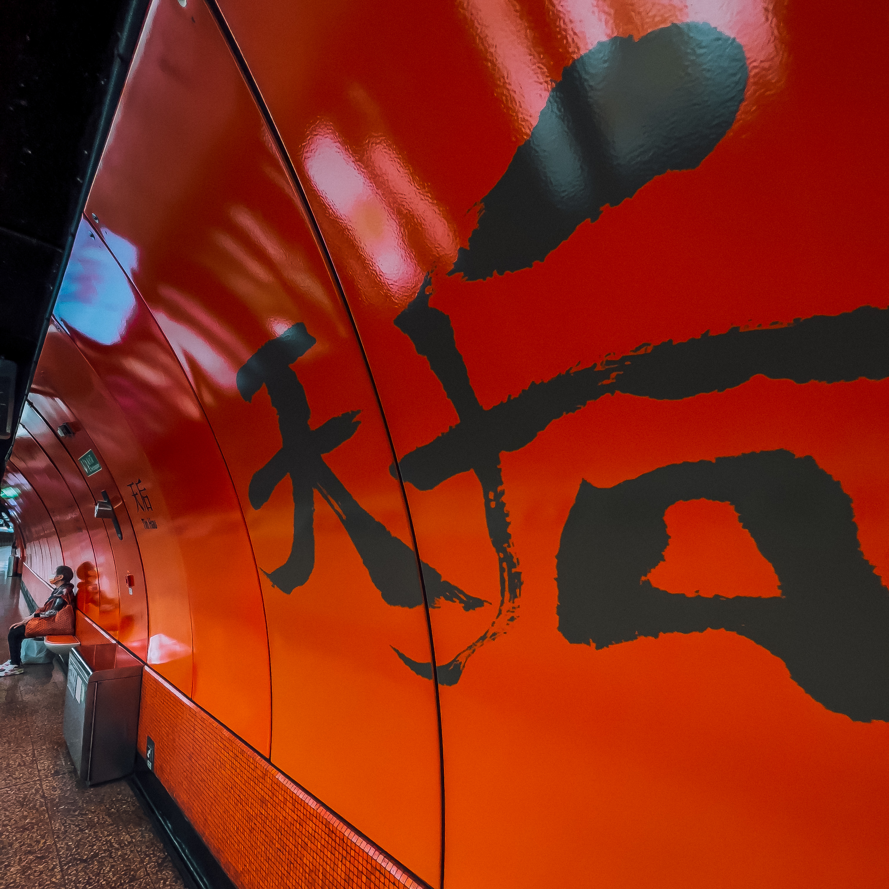 Close-up of a vibrant orange subway train with a large black kanji character on the side