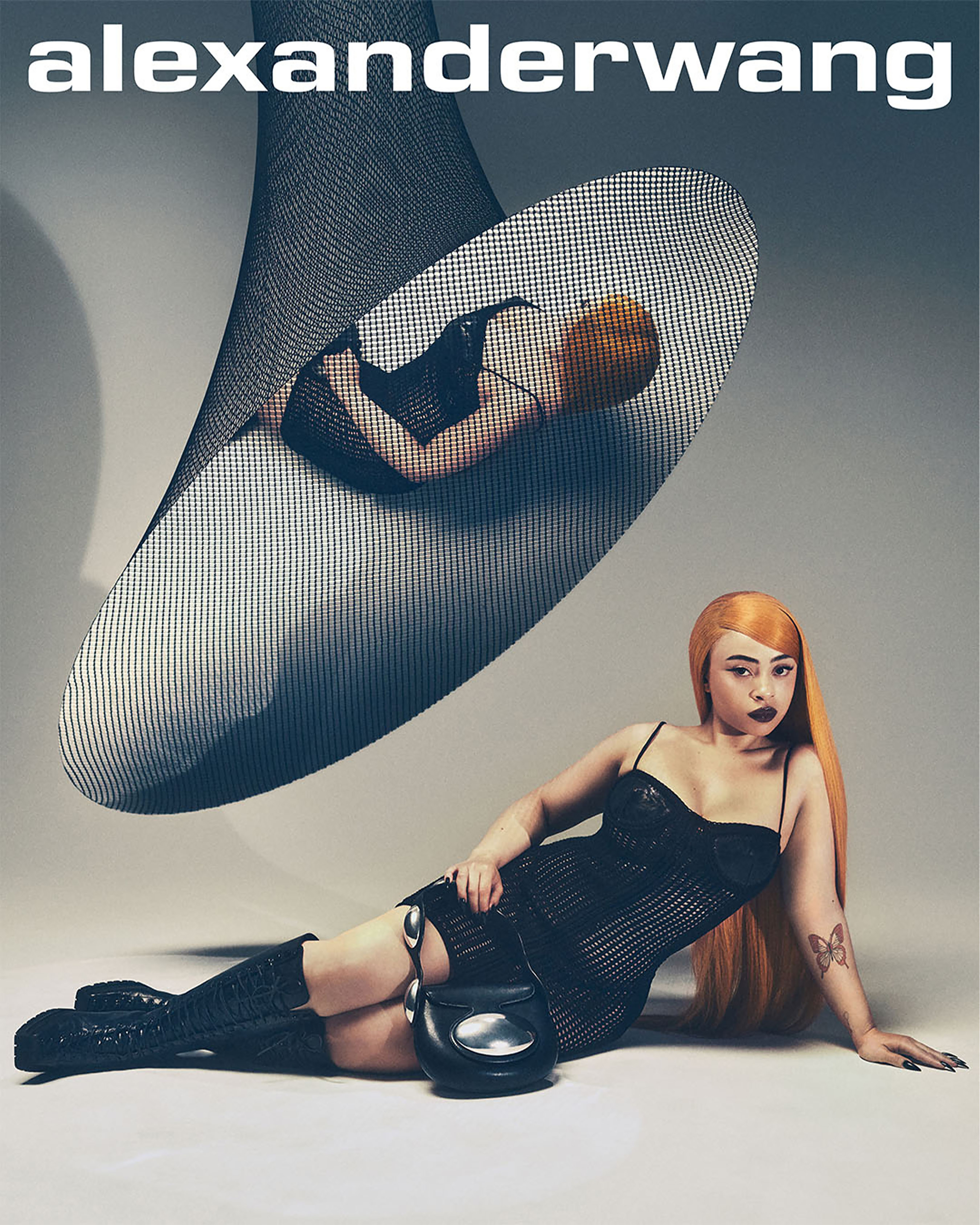 Woman in black dress and knee-high boots posed under oversized hat for Alexander Wang ad