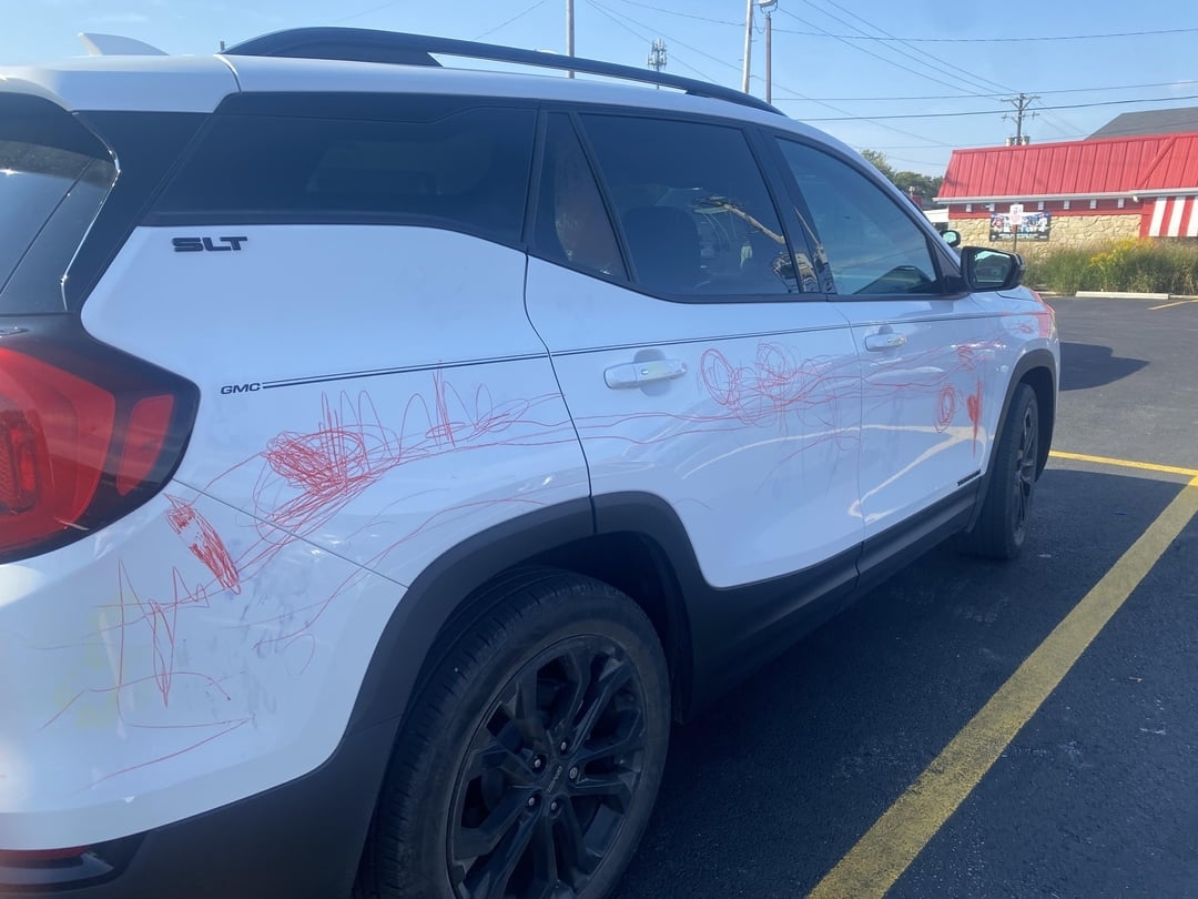 White SUV with child&#x27;s red scribble drawings on the side