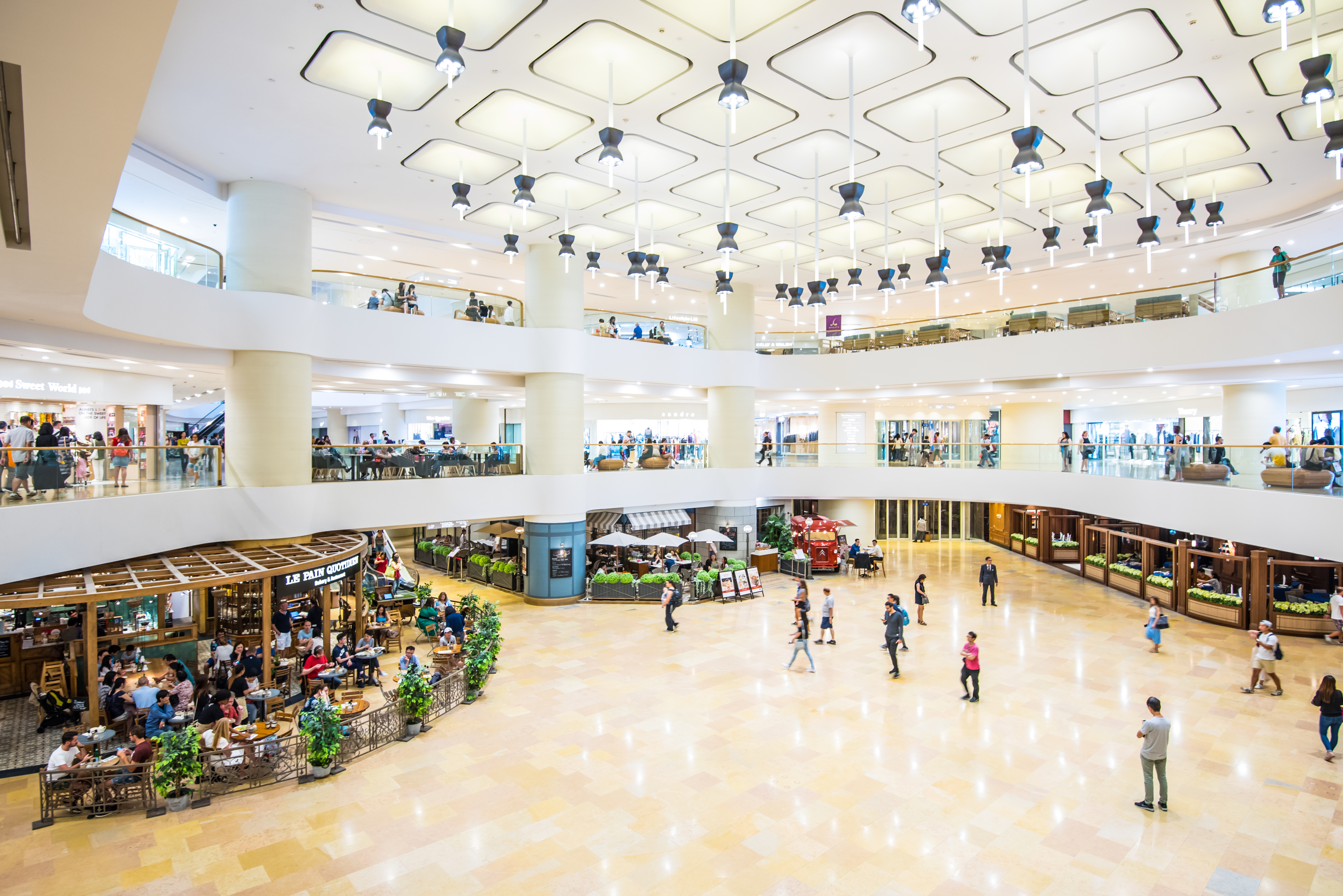 Interior of a busy multi-level shopping mall with various stores and shoppers