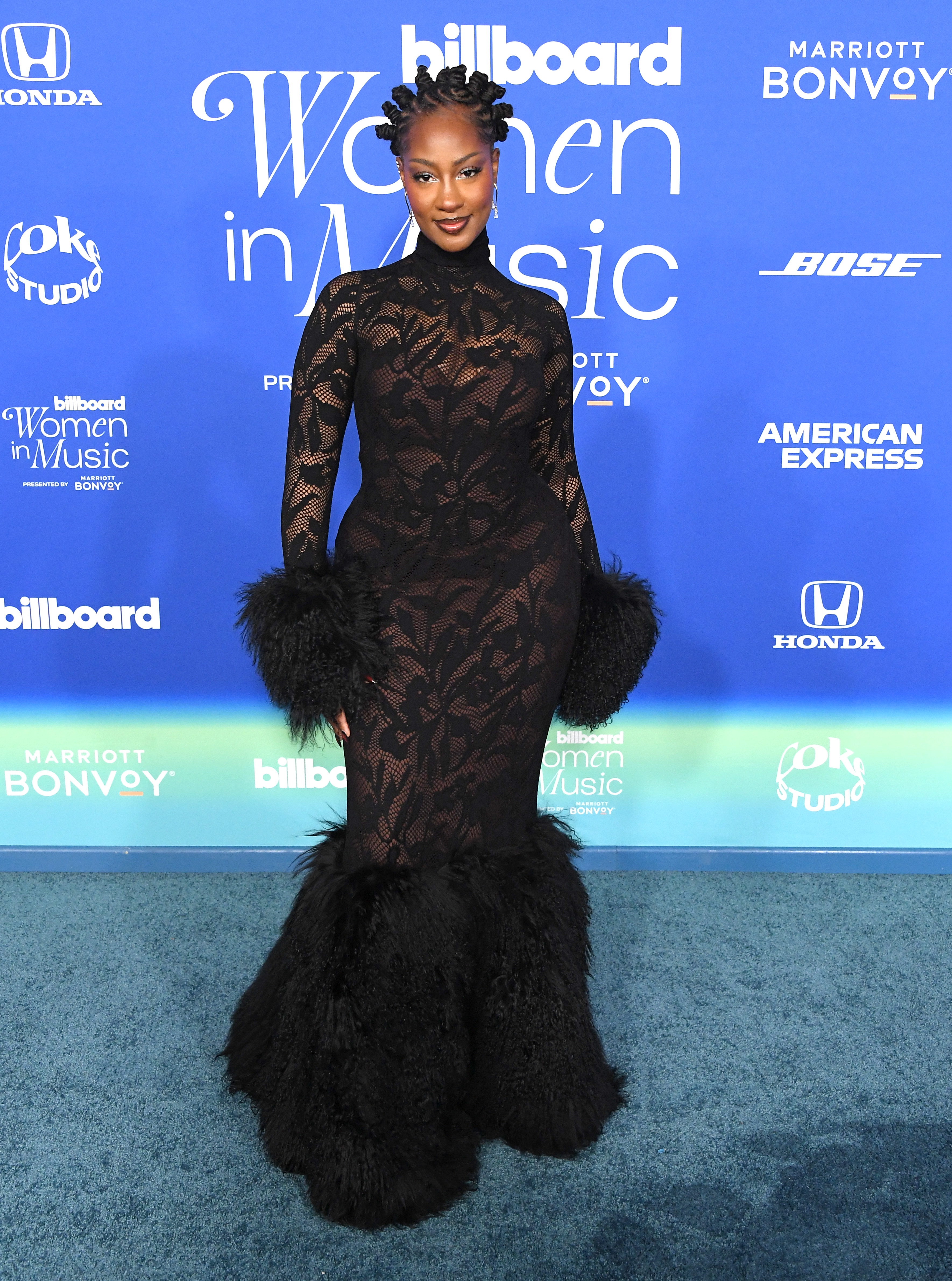 tems in a sheer long gown with feathers at the hems