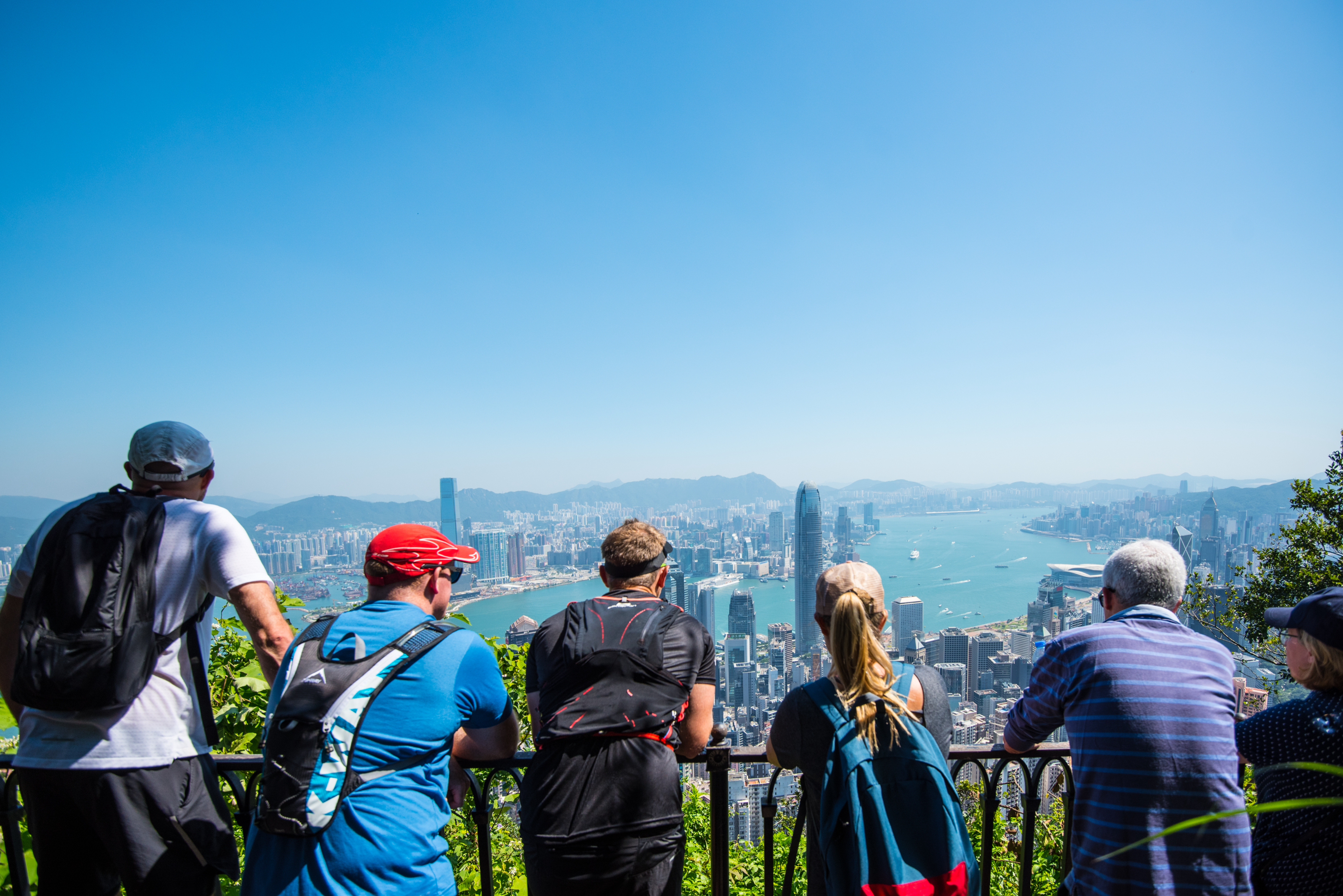 People at a viewpoint overlooking a city skyline and harbor