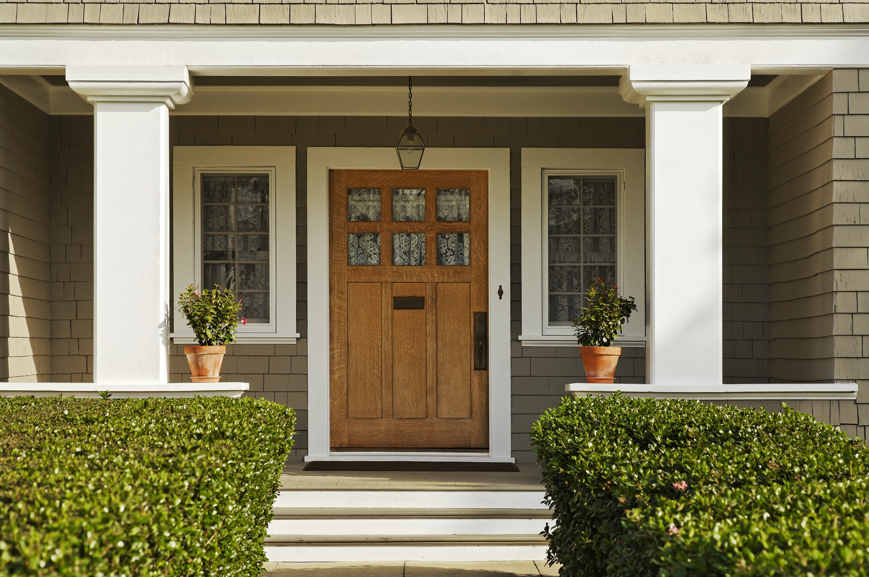 Classic home entrance with a wooden door and symmetrical potted plants