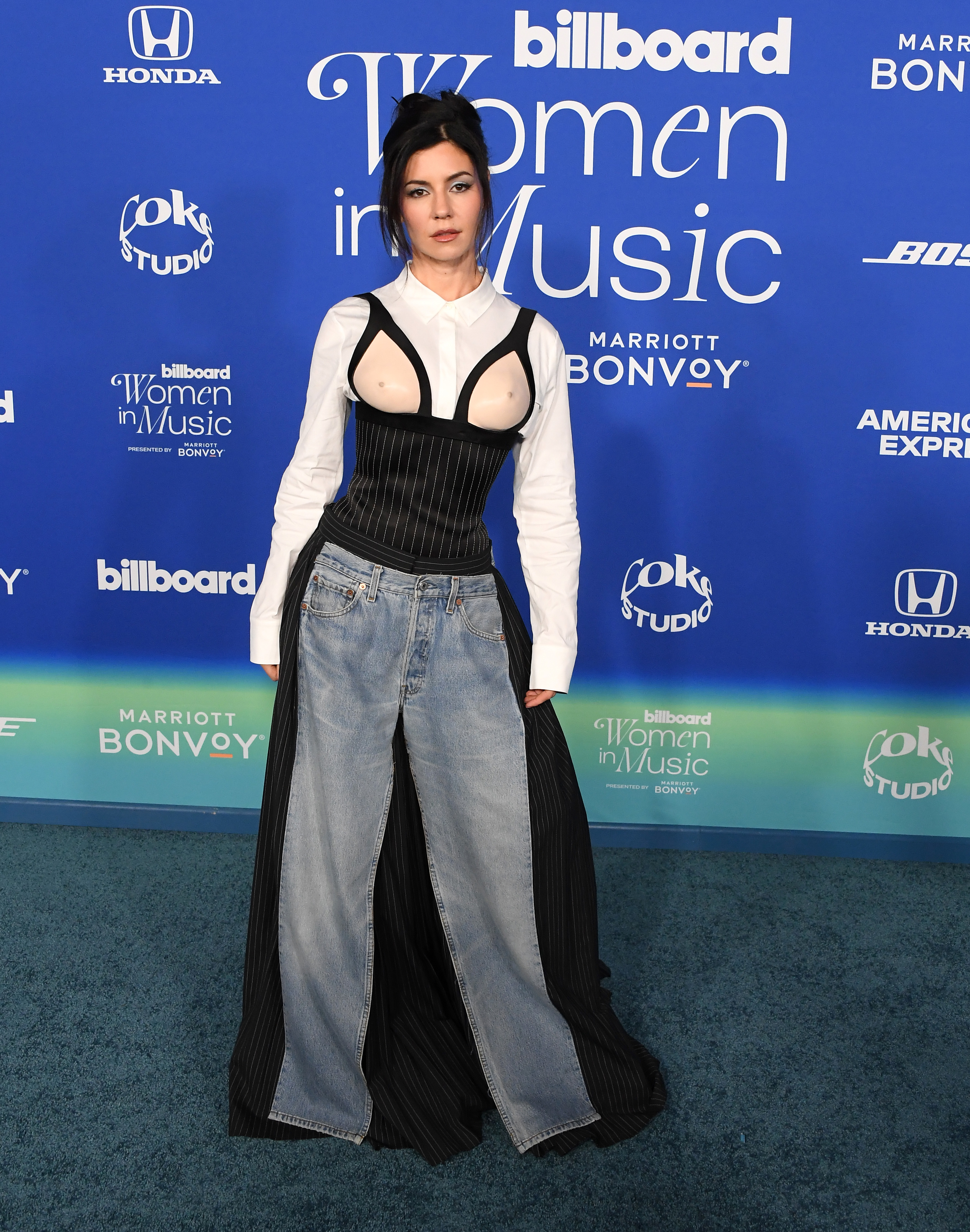 Marina in a pinstripe corset top over a long sleeve buttondown and half denim and pinstripe pants