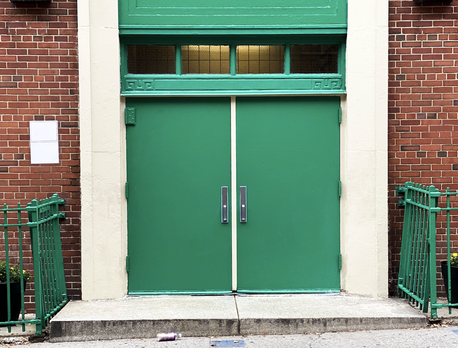 Double doors with metal handles on a brick building, indicating a formal entrance or workplace