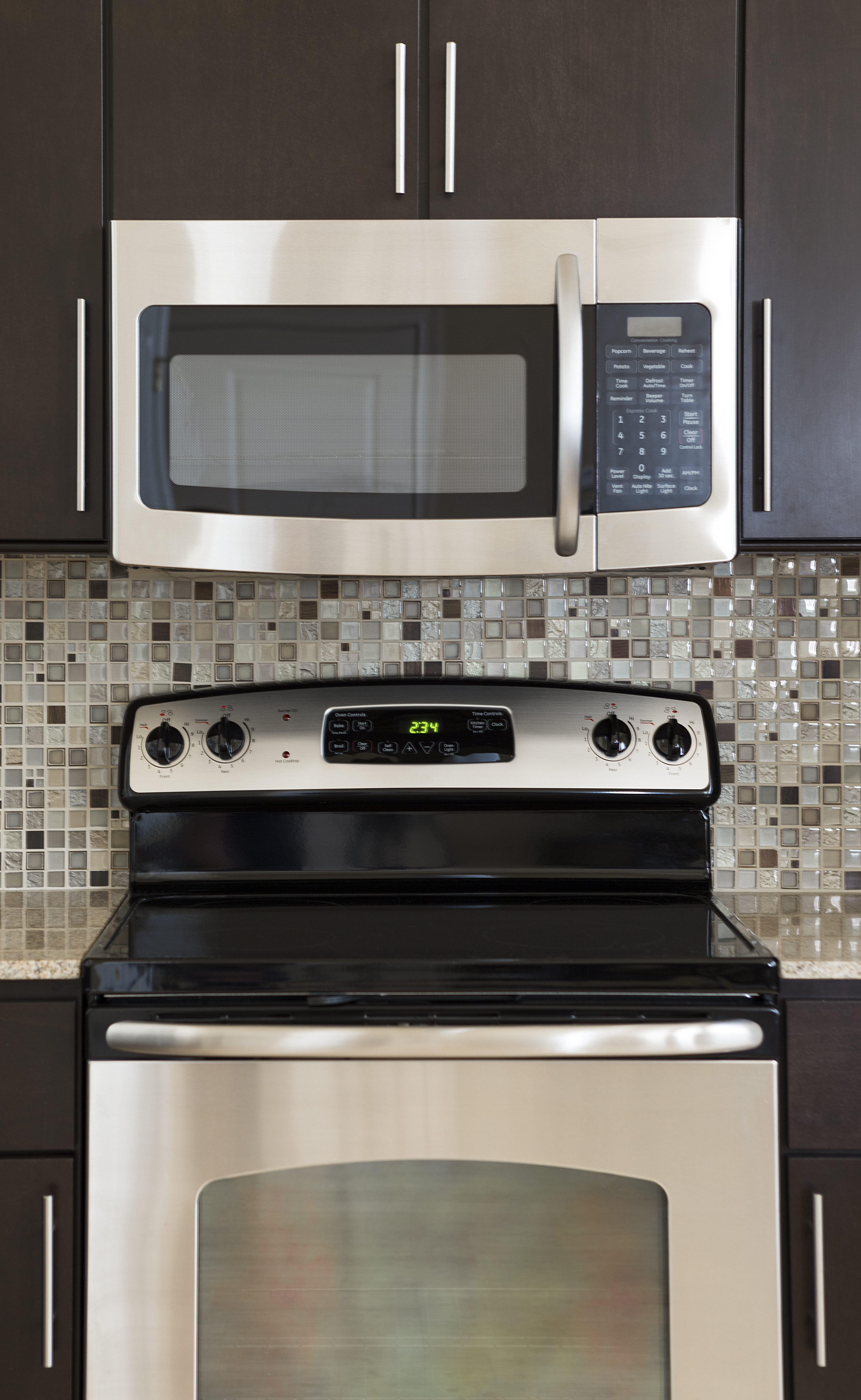 Modern kitchen with microwave above a stove and oven, set against a mosaic backsplash