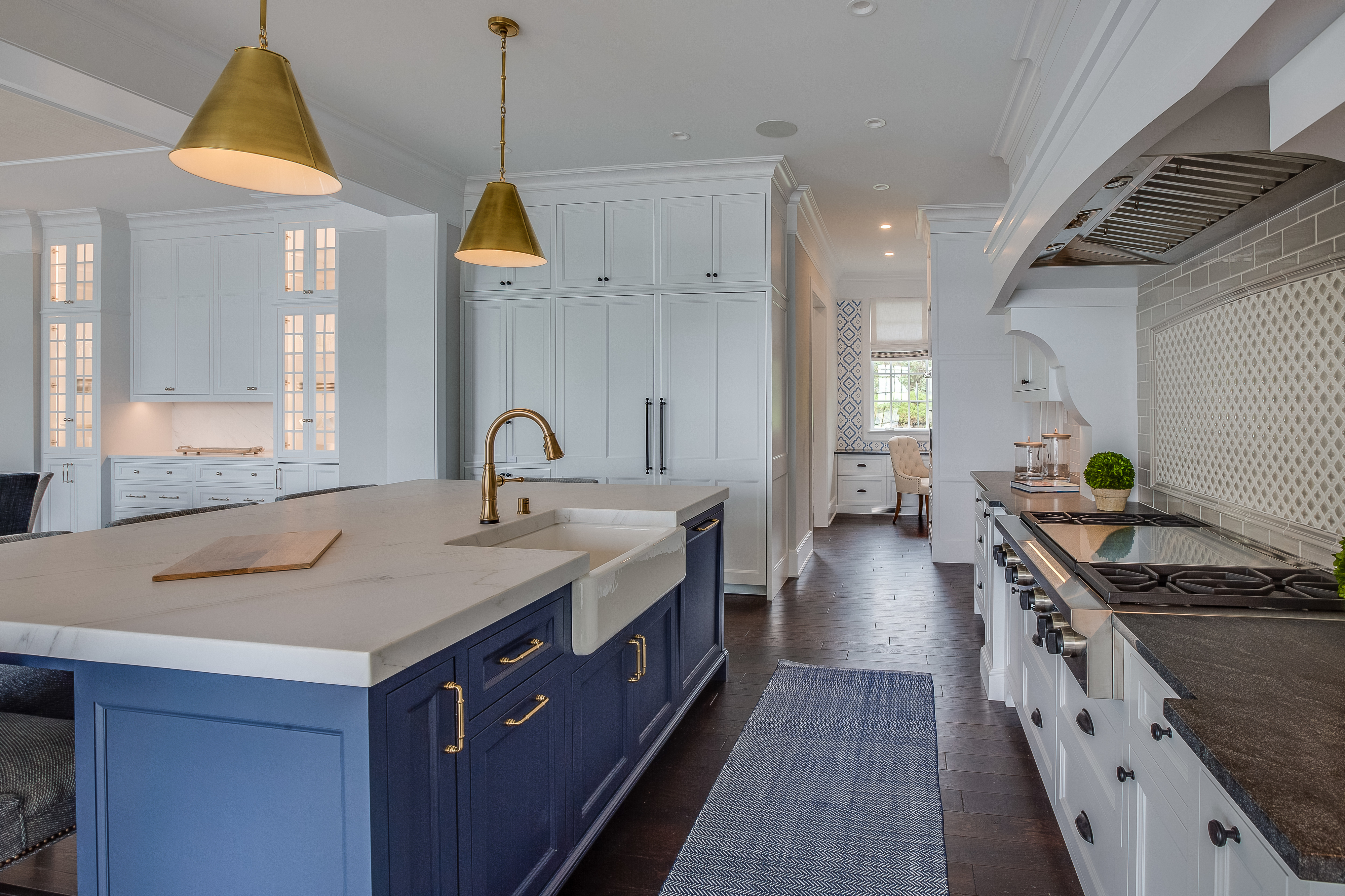 Modern kitchen with white cabinetry, blue island, and gold fixtures