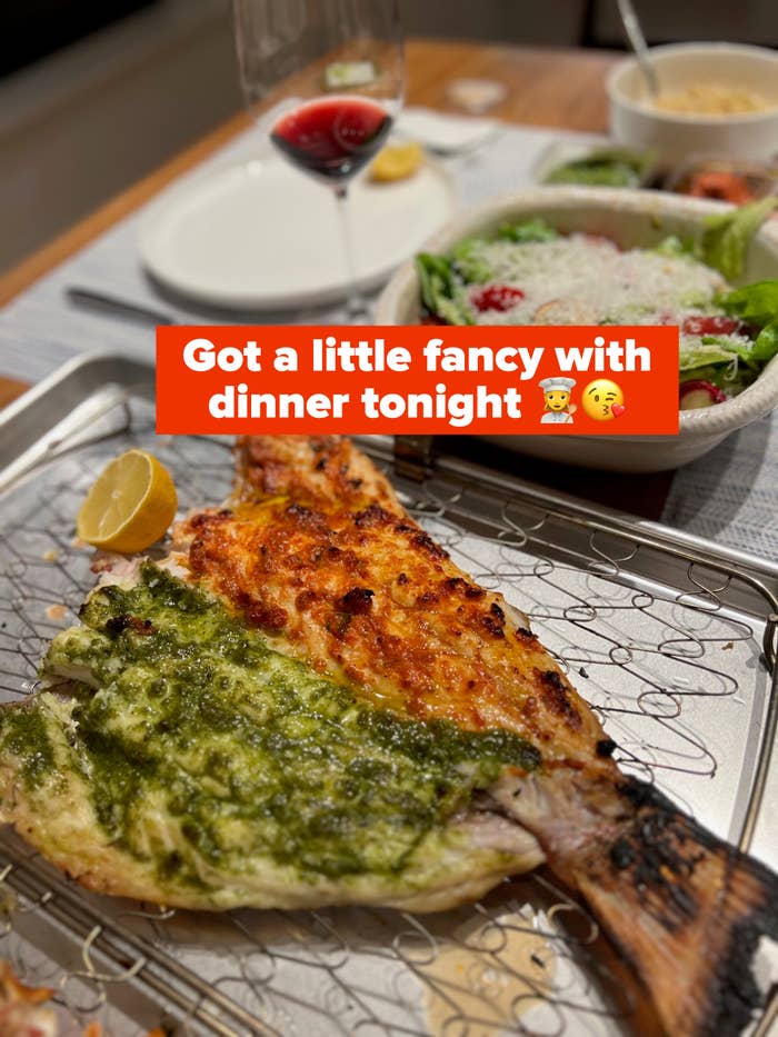Grilled fish beside a salad and drinks on a dining table