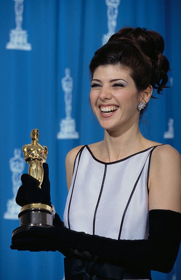 Marisa in sleeveless gown smiling, holding an Oscar award