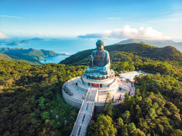 Aerial view of the large Tian Tan Buddha statue surrounded by forest in Hong Kong