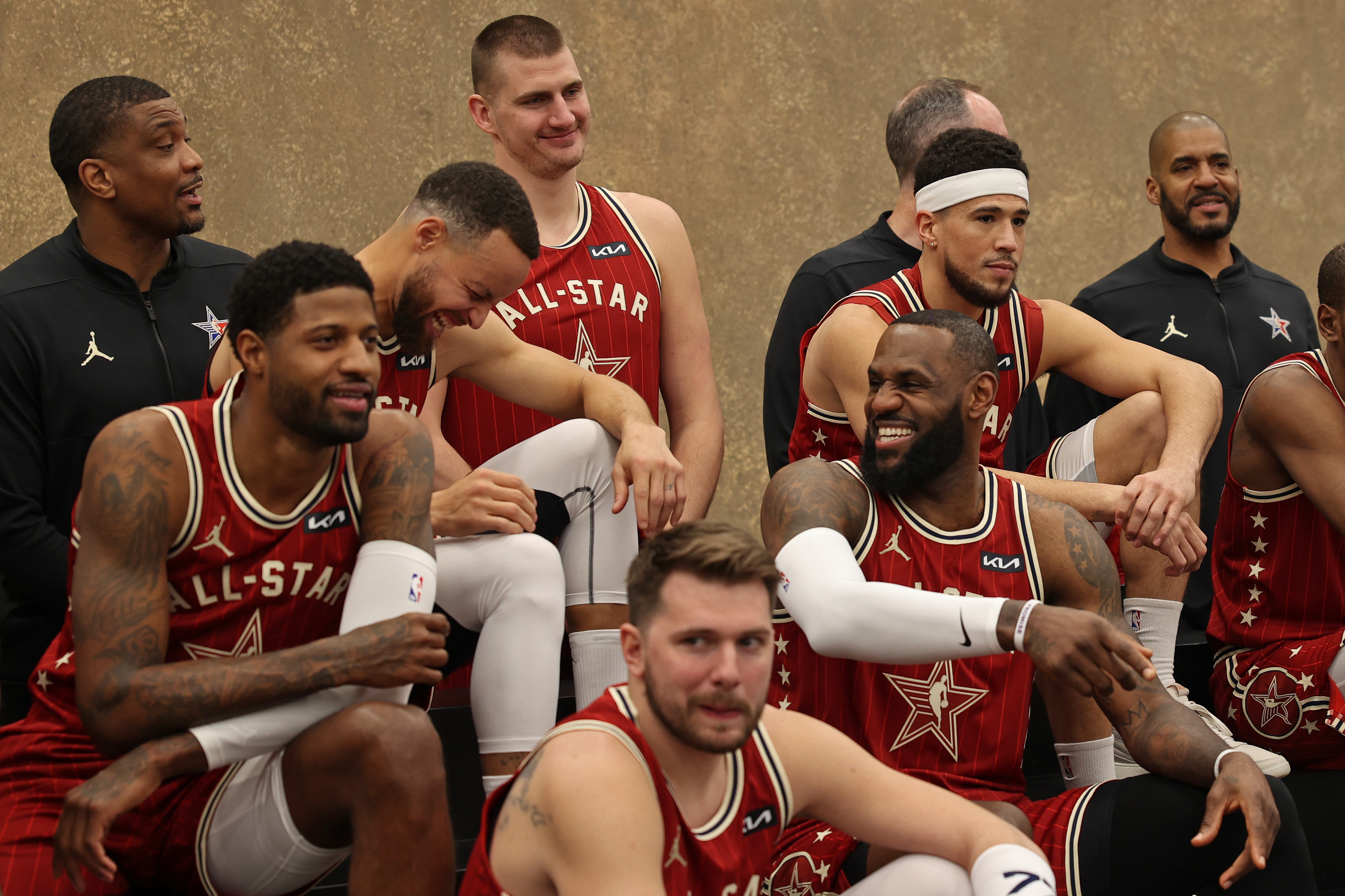 Professional basketball players in All-Star jerseys sitting and chatting