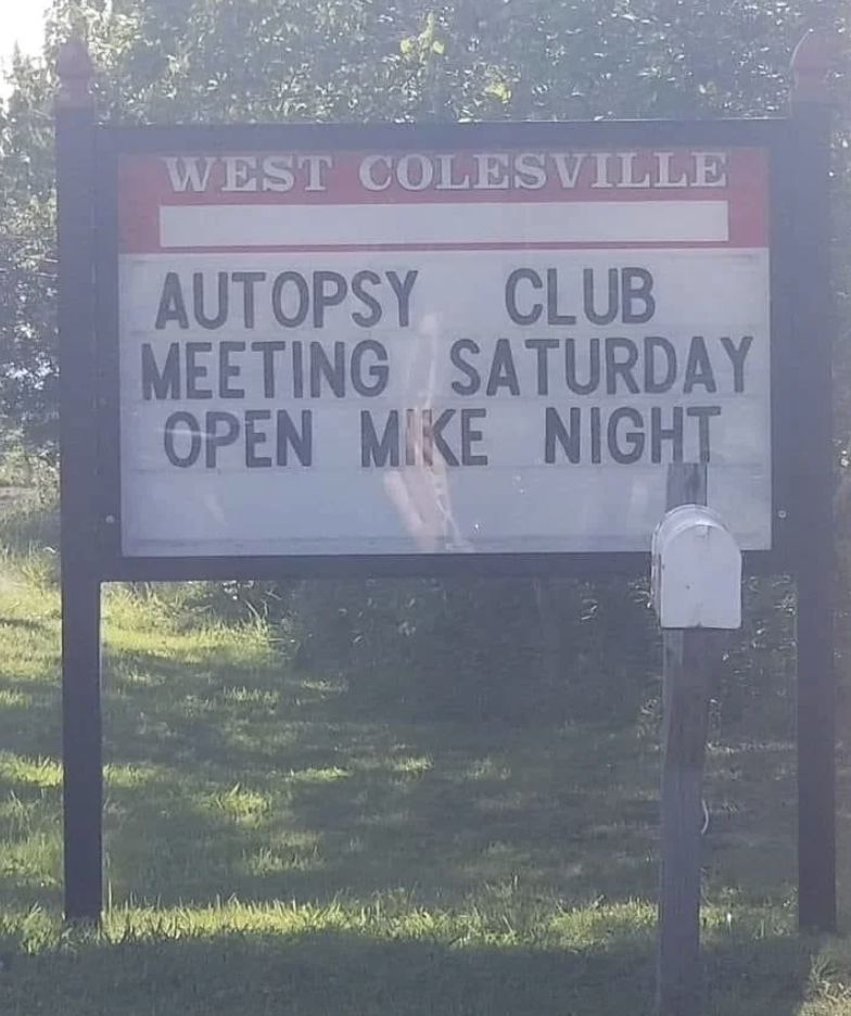 Sign reads "WEST COLESVILLE AUTOPSY CLUB MEETING SATURDAY OPEN MIKE NIGHT"
