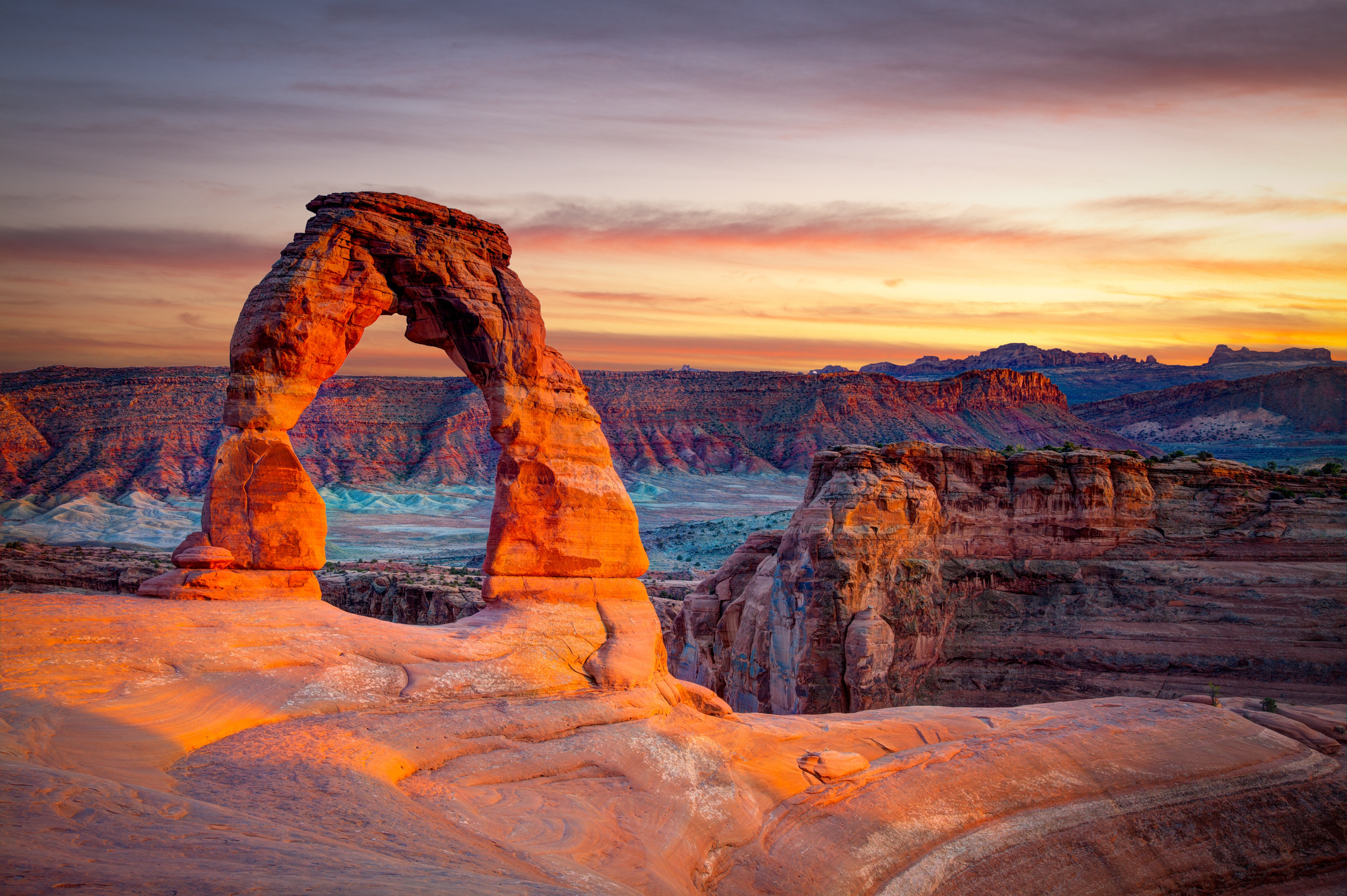 Delicate Arch in Arches National Park at sunset, rock formations in the background