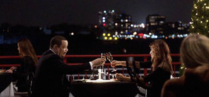 A man and woman clinking drinks at the dinner table