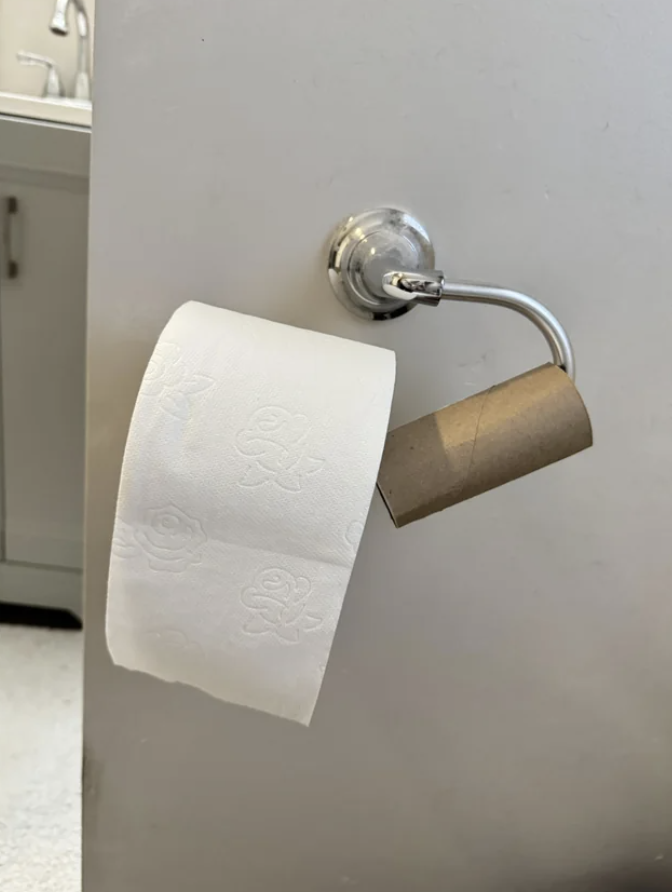 Toilet paper roll is empty and a new one is next to it