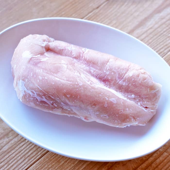 生の鶏の胸肉が白い皿にのっている。
