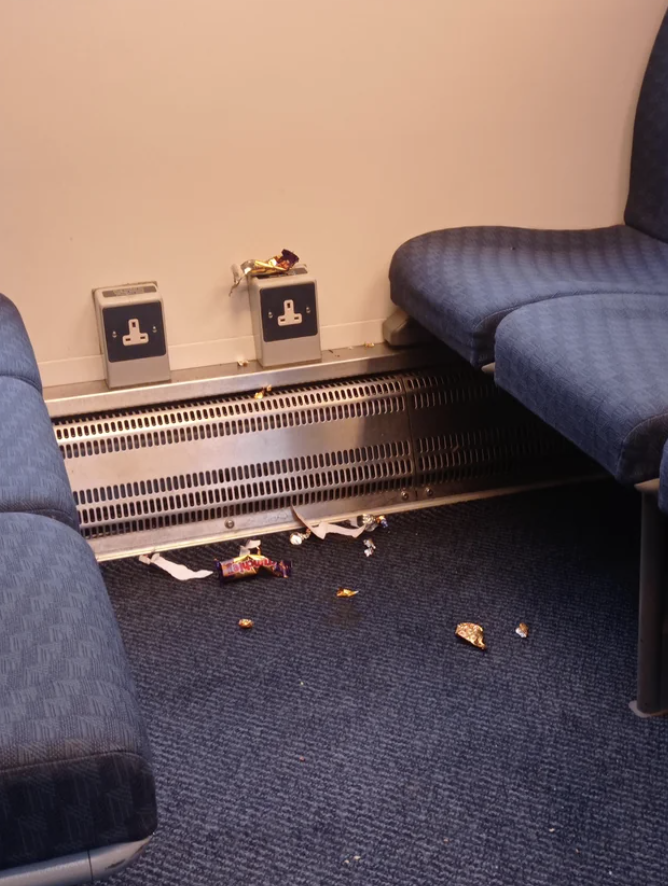 An office corner with litter on the carpet and two wall outlets above a heater