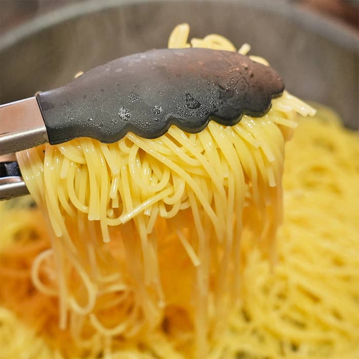 鍋から取り上げたスパゲッティをはさむトング。