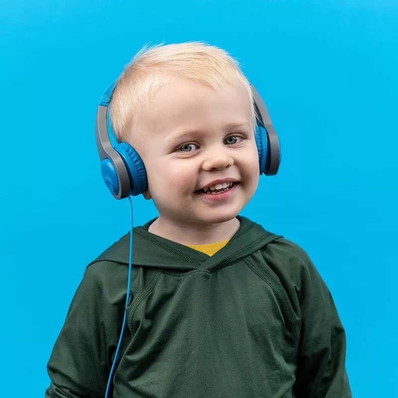 Child wearing headphones and a green shirt smiles against a blue background
