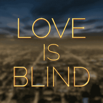 Glowing text &quot;LOVE IS BLIND&quot; above silhouettes of a cityscape at dusk