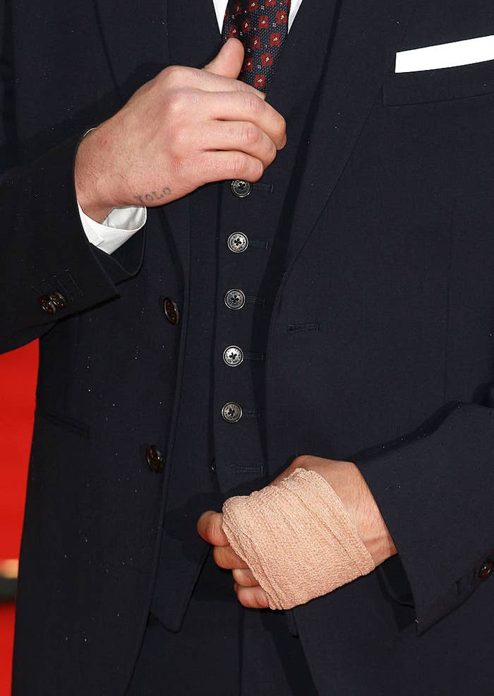 Person adjusting a black suit jacket with a wrapped wrist, focus on midsection