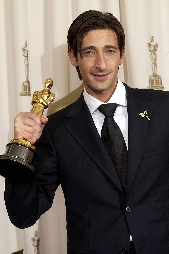 Adrien in a tuxedo smiling, holding his Oscar