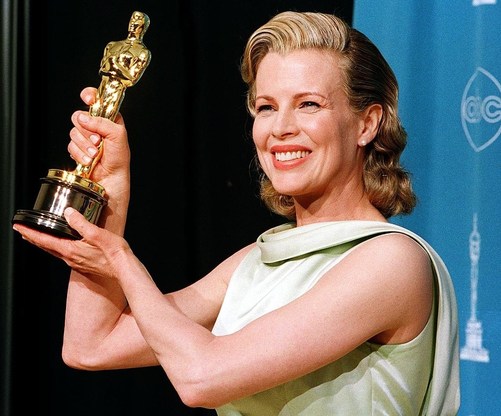 Kim holding an Oscar, smiling in a sleeveless gown