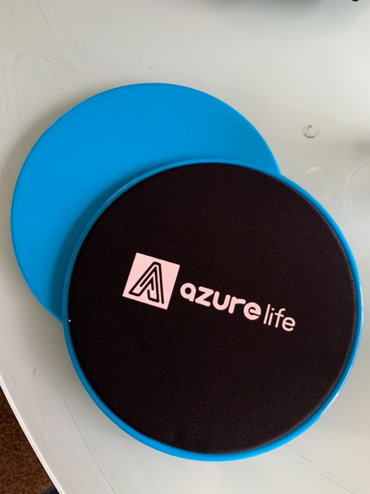 Two silicon grip strengtheners next to an Azurelife exercise pad on a table