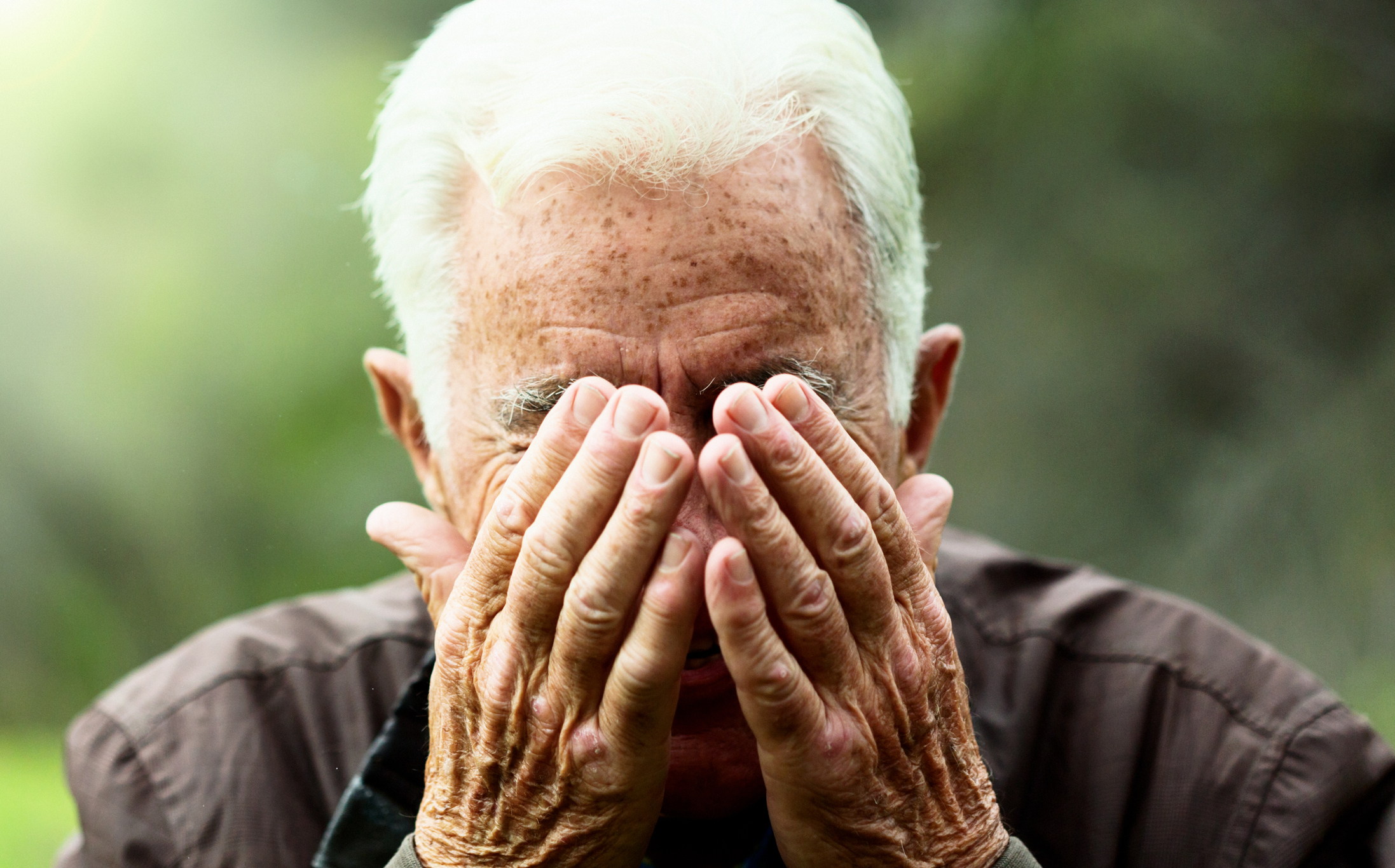 Older man covering his face with his hands