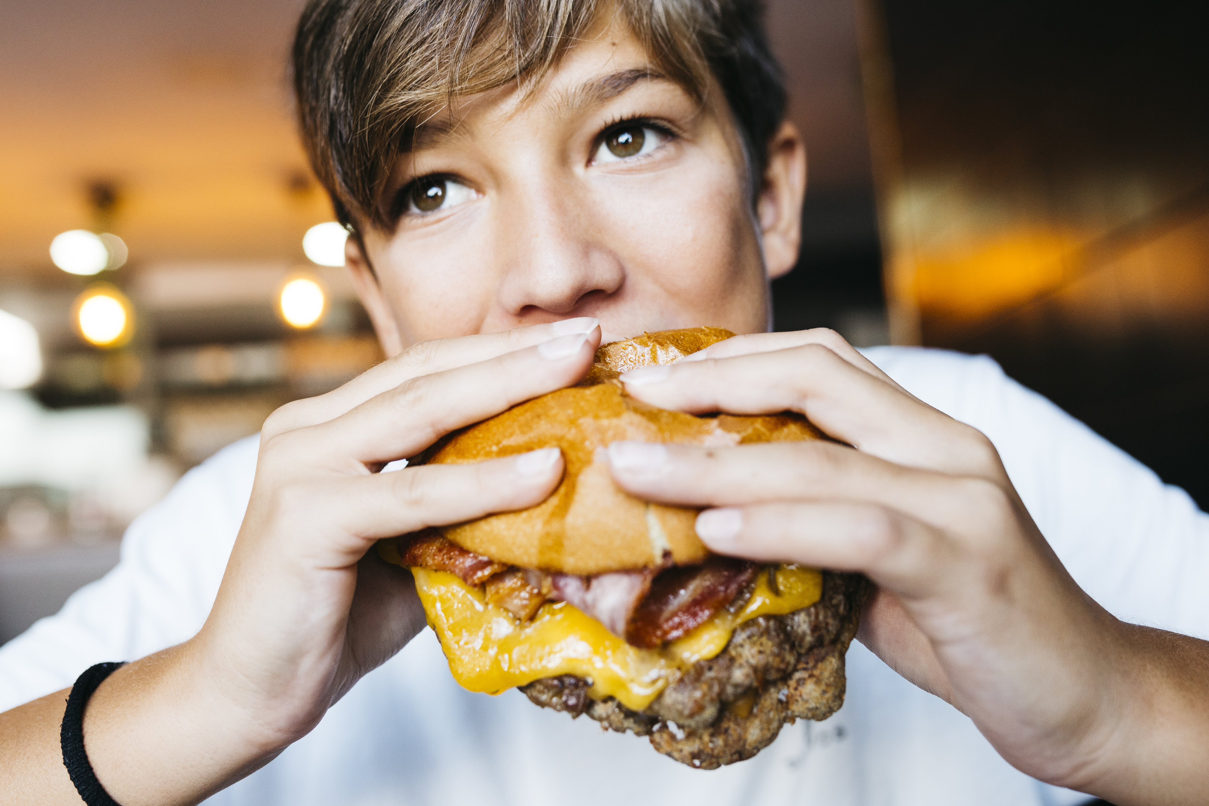 Person eating a large cheeseburger with both hands