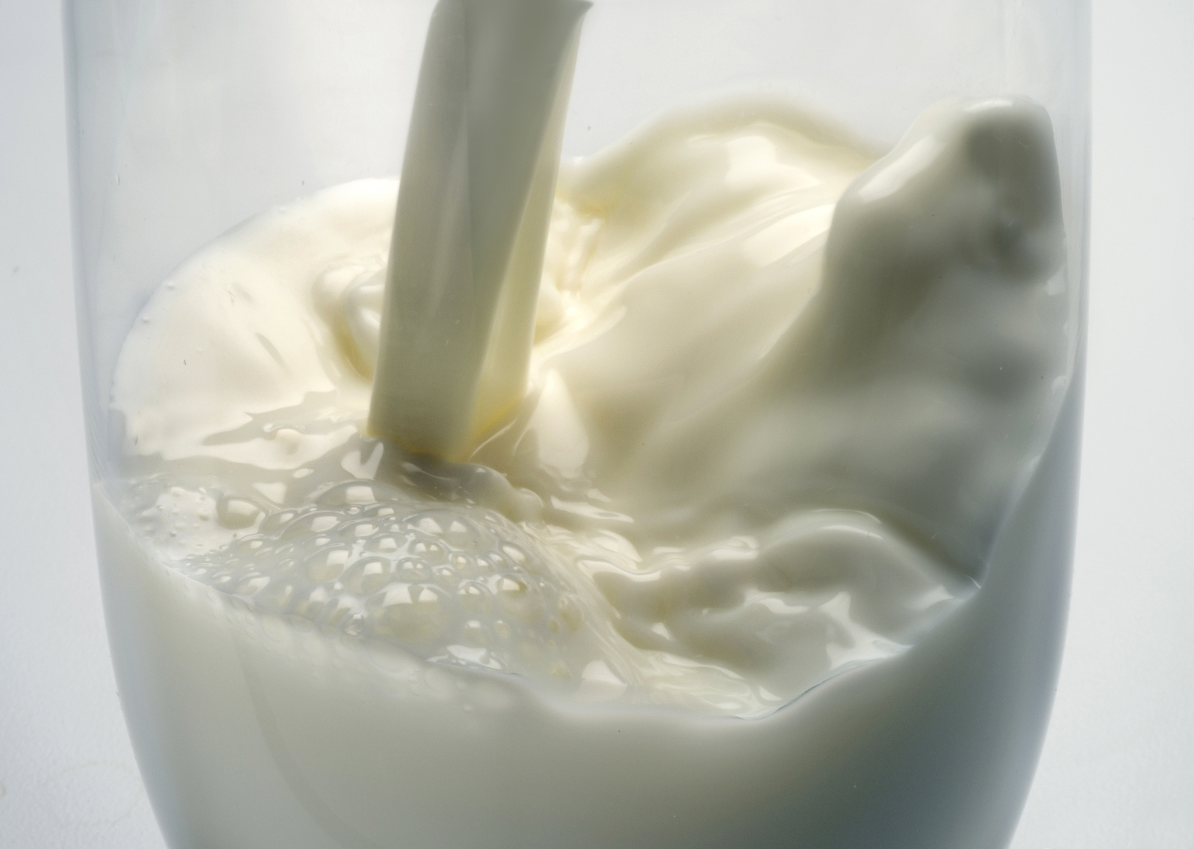Close-up of milk being poured into a glass, creating a splash