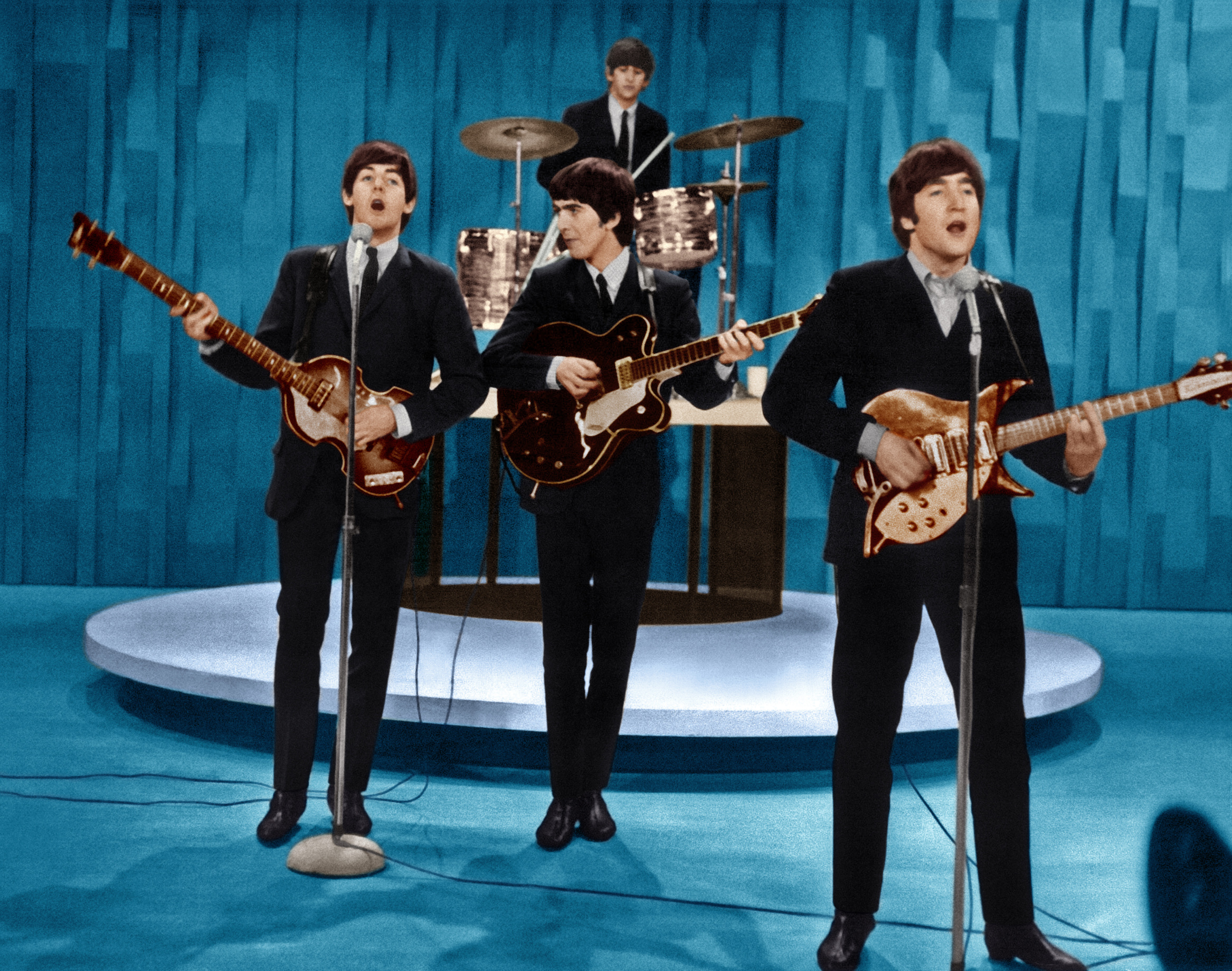 The Beatles performing onstage with guitars and a drum set