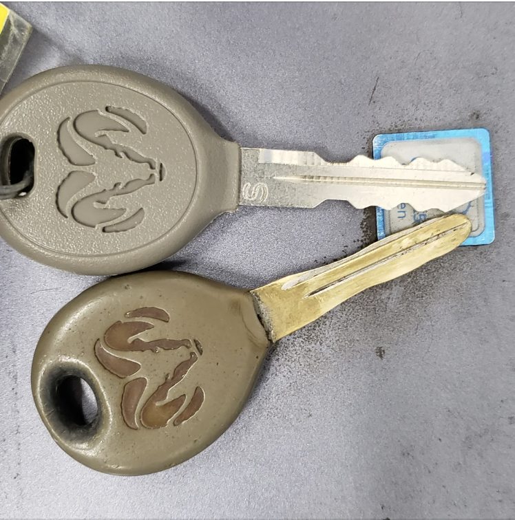 Three keys on a surface, two with oversized decorative heads, one with a blue tag attached
