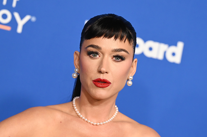 Celebrity with pearl necklace and earrings, styled hair, red lipstick, looking at the camera