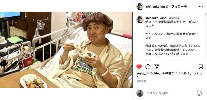 病院のベッドに座り、食事をしている人物の写真です。