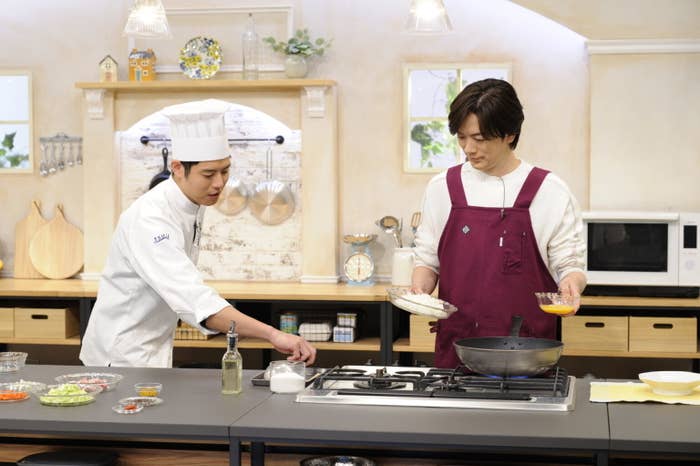 二人の男性が料理をしているキッチンのシーンです。
