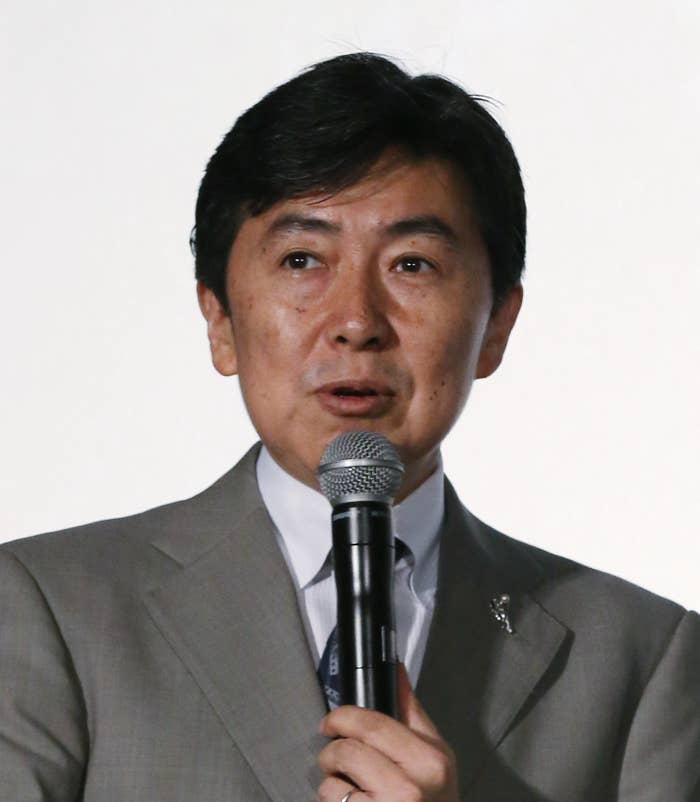 スーツを着た男性がマイクで話している。