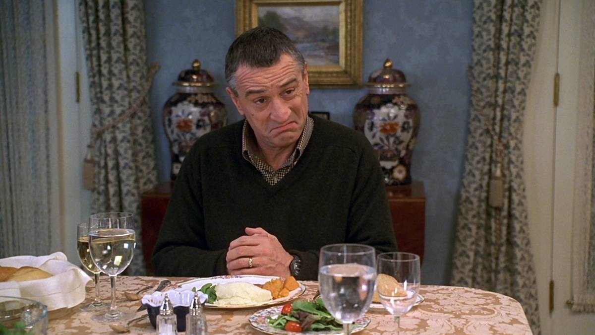 Man at dinner table with a concerned expression, plate of food in front of him