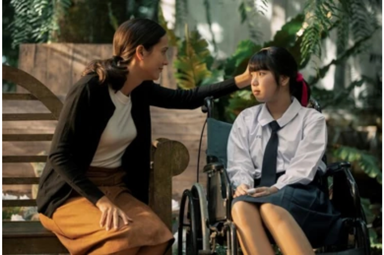 Two characters from a film, one seated on a bench and one in a wheelchair, appear to have a conversation