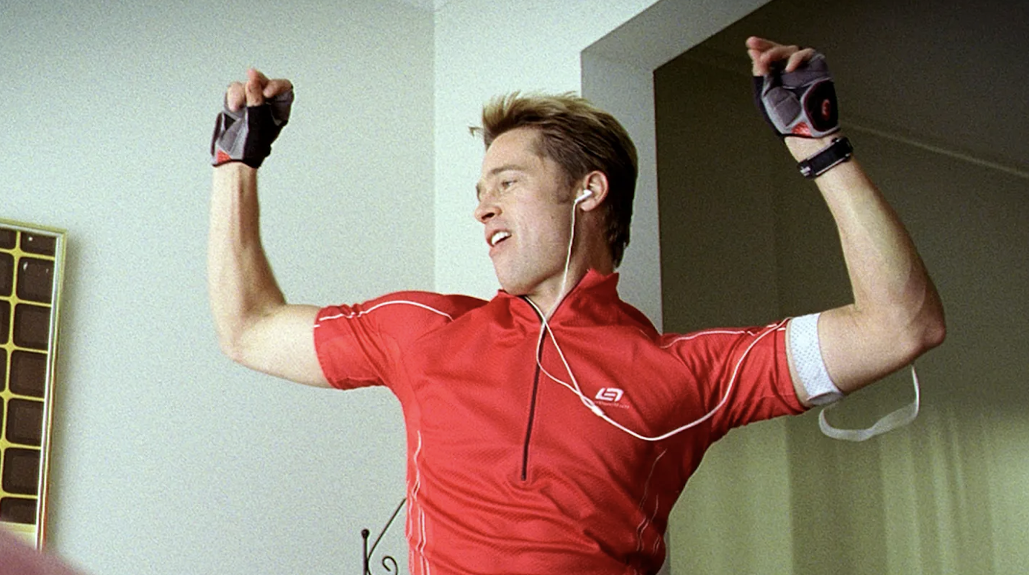 Man in red sportswear with headphones dancing with raised fists