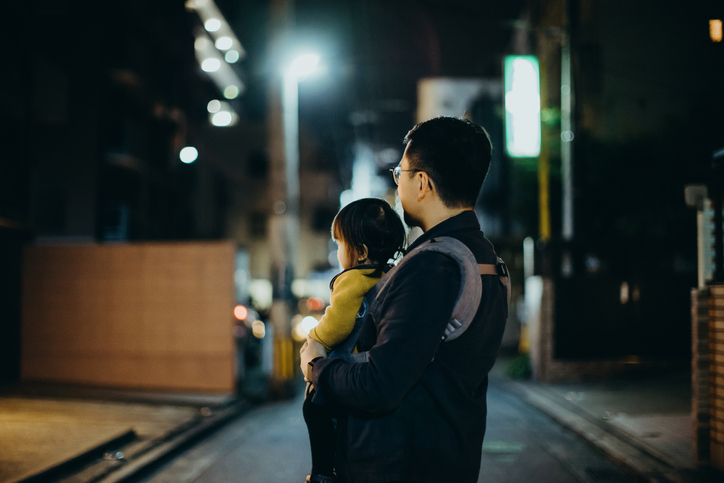 Man carrying a child on his back at night on a city street
