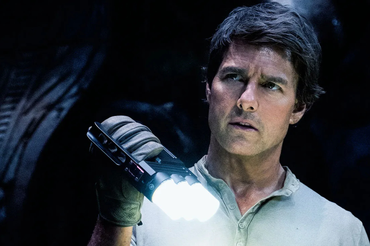 Tom Cruise in a tense scene holding a flashlight, looking intently to the side