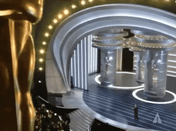 Oscars stage with a large Oscar statue on the left and people seated in the audience