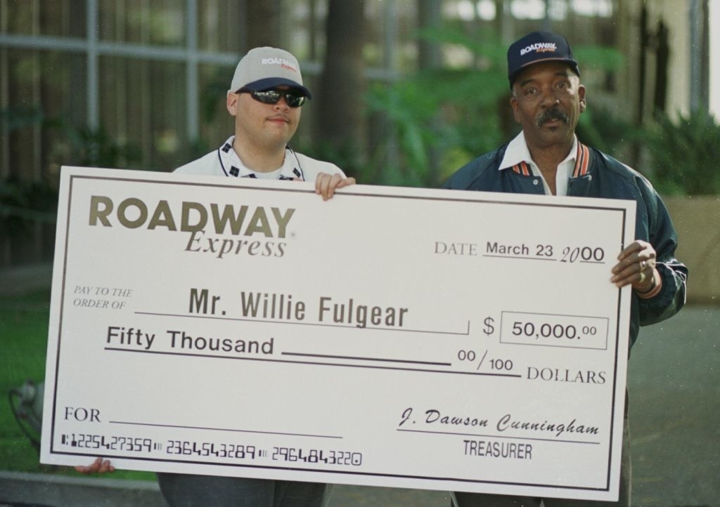 Two men holding a large promotional check from Roadway Express made out to Mr. Willie Fulgear