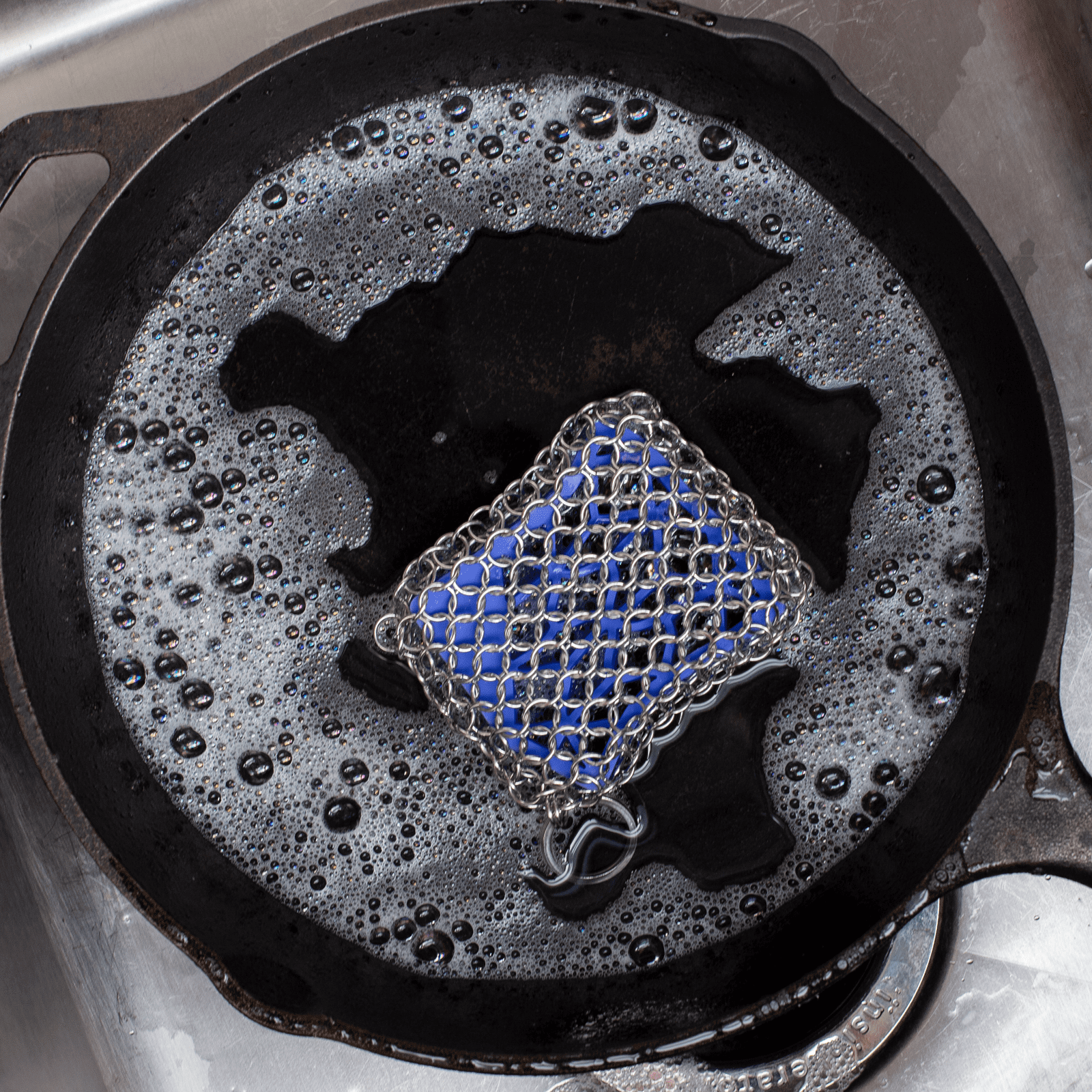 Cast iron skillet with soapy water and a chainmail scrubber