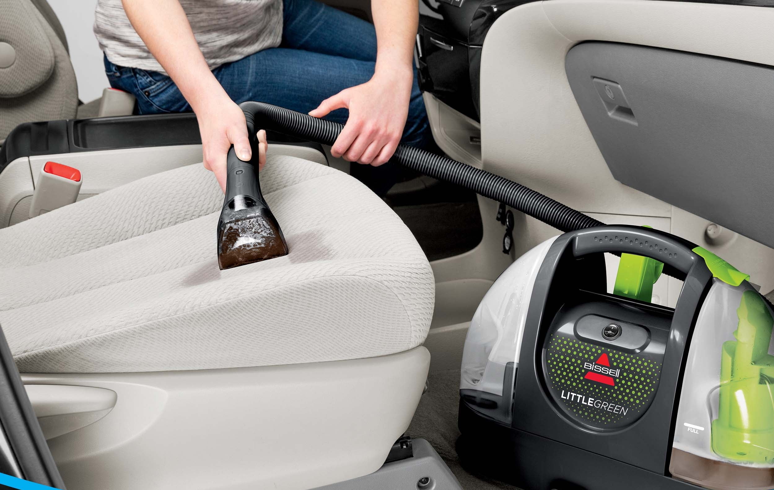 Model cleaning a car seat using a portable carpet cleaner with the text &quot;Strong Spray &amp;amp; Suction&quot;