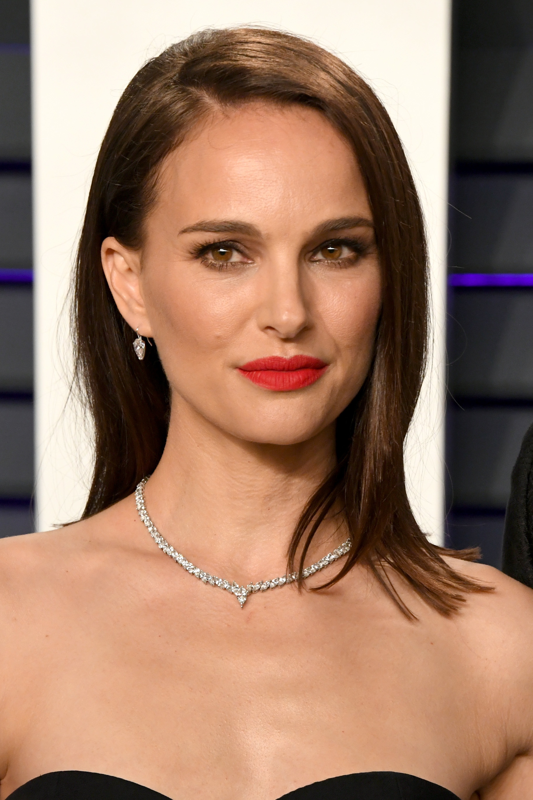 A close-up of Natalie with red lipstick and wearing a diamond necklace