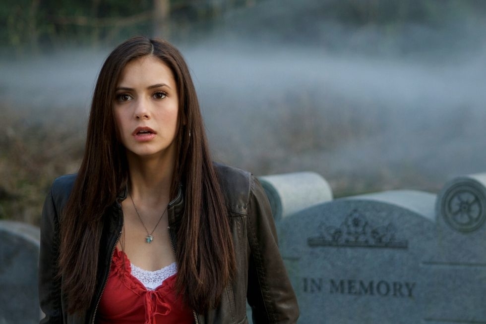Elena Gilbert from the Vampire Diaries standing in a cemetery with a pensive expression