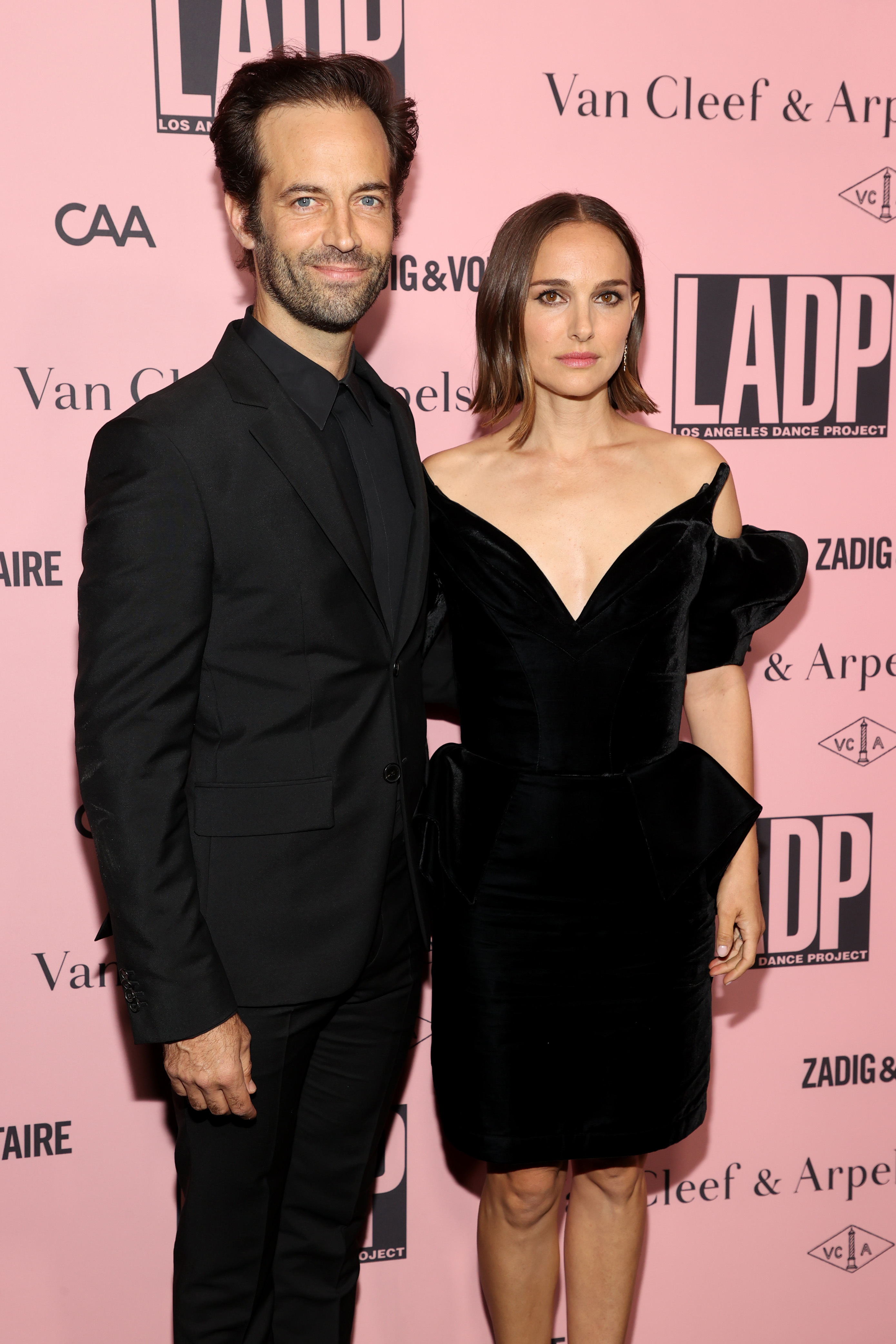 The couple at a media event together, he in a black suit and she in a black off-the-shoulder velvet dress