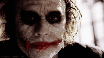 Heath Ledger as the Joker, close-up, wearing clown makeup with smeared red lips, disheveled hair, and a scarred smile